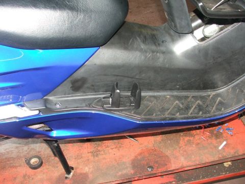2006 Honda Reflex - Close-up view of a blue scooter's floorboard, showing textured grip and footrest mounts.