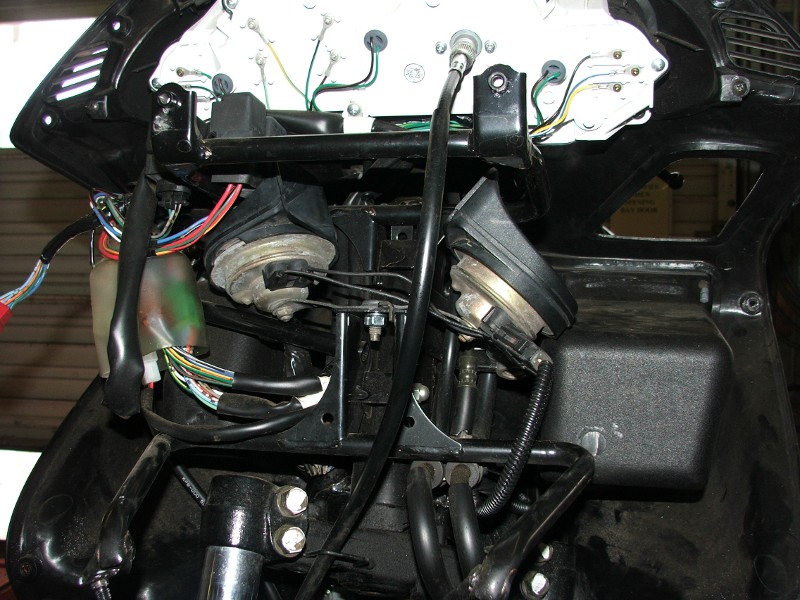 Motorcycle front end disassembled, showing wiring, horns, and part of the instrument cluster