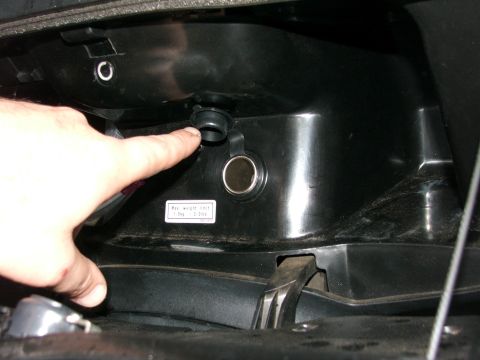 2006 Honda Reflex - A finger points to an open power outlet above a cigarette lighter socket in a vehicle's interior.