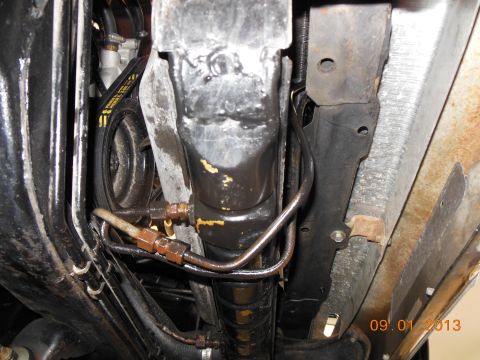 1979 Ford F-150 - Close-up of the transmission cooler lines and a belt, showing some wear and tear.