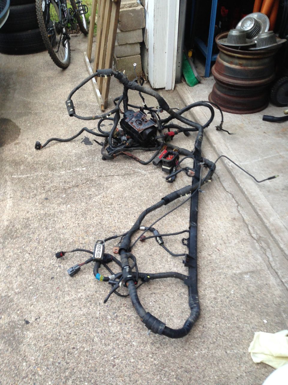 Engine wiring harness on concrete, with bicycle and tires in background