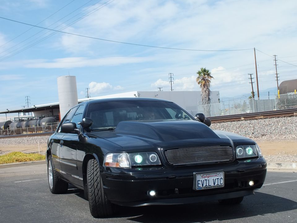 Black customized full-size sedan, front 3/4, billet grille, halo headlights, EVIL VIC plate