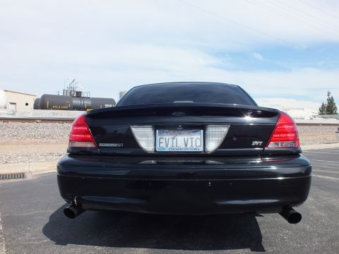 2003 Ford Crown Victoria - Rear view of a black Ford Crown Victoria with an SVT badge, dual exhaust and an EVIL VIC plate over a CROWN VICTORIA frame.