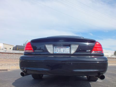 2003 Ford Crown Victoria - Rear of a black Ford Crown Victoria showing Ford oval, SVT and Supercharged badges, dual exhaust and an EVIL VIC plate.