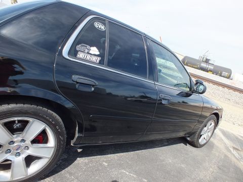 2003 Ford Crown Victoria - Close view of the rear door, quarter panel, and chrome wheel of a black sedan with window decals.