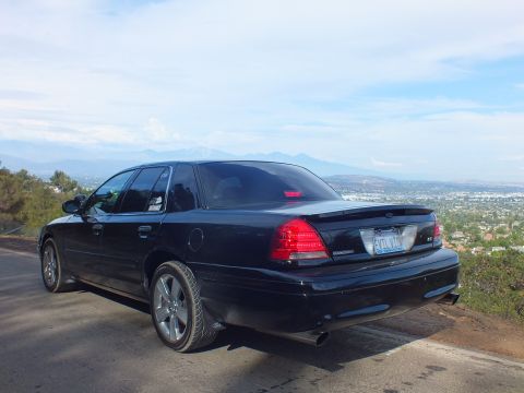 2003 Ford Crown Victoria - Rear driver-side view of a black full-size sedan with a trunk spoiler, dual exhaust, and EVIL VIC plate above a valley.