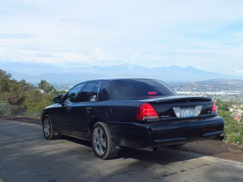 2003 Ford Crown Victoria - black Ford Crown Victoria sedan parked at a ridge overlook, photographed from the rear three-quarter against distant mountains.