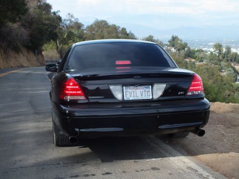 2003 Ford Crown Victoria - Direct rear view of a black Ford Crown Victoria sedan with illuminated tail and brake lights and an 'EVIL VIC' license plate.