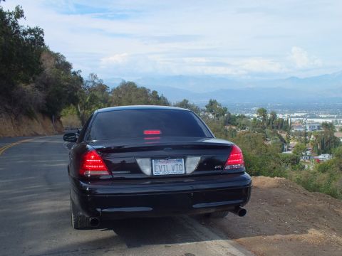 2003 Ford Crown Victoria - black Ford Crown Victoria sedan parked at a curving overlook, rear three-quarter view with a city and mountains in the distance.