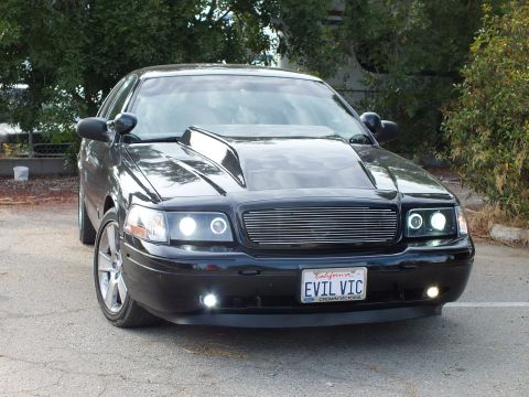 2003 Ford Crown Victoria - Front view of a black Ford Crown Victoria with cowl-induction hood, billet grille, halo headlights and an EVIL VIC plate.