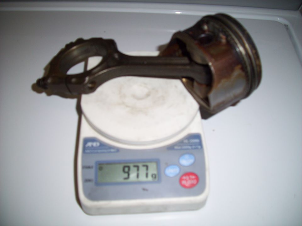 Piston and connecting rod assembly on a digital scale reading 977g