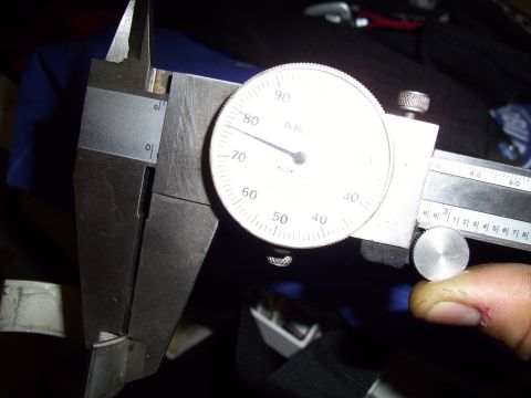 1995 Ford Probe - A dial caliper is used to precisely measure a component, with the dial indicating a measurement.