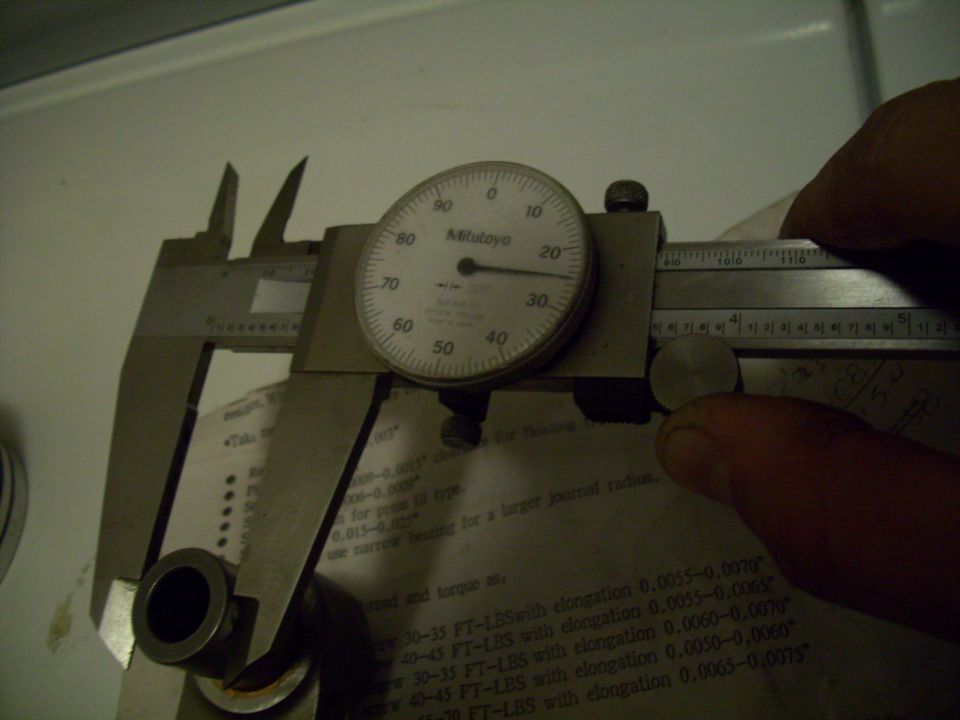 Dial caliper measuring a small metal part with a Mitutoyo dial indicator