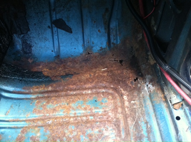 Rusted blue interior floor pan with visible wiring and black conduit