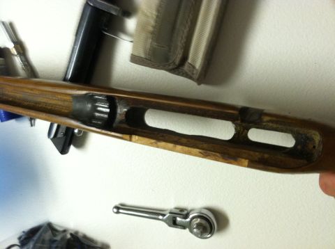 1989 Ford Bronco - Close-up view of the internal mechanism of a wooden gun stock, with a ratchet tool nearby.