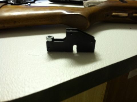 1989 Ford Bronco - A black metal gun accessory is placed on a table next to a wooden gun stock.