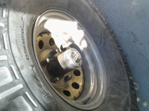 1986 Ford Bronco - A close-up view of a vehicle's wheel hub and tire, showing the locking mechanism and rim details.