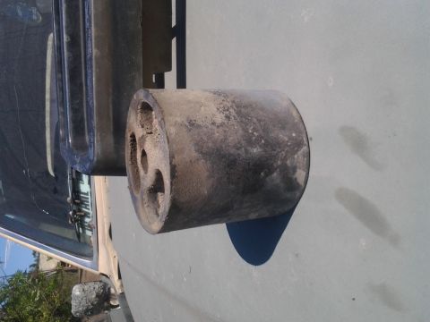 1986 Ford Bronco - A close-up view of a vehicle's exhaust pipe and its mounting bracket, showing signs of wear and tear.