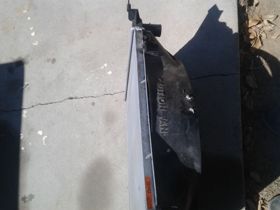 Radiator fan shroud with "CAUTION FAN" text, lying on concrete