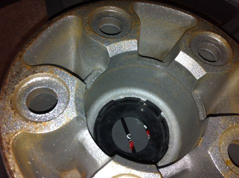 1995 Ford Mustang - A close-up view of a wheel hub and its center cap, showing rust and some red markings within the cap.
