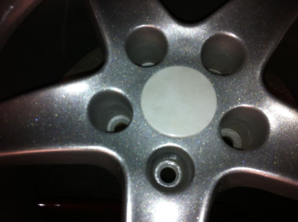 Close-up of a silver alloy wheel with five spokes and a blank white center cap