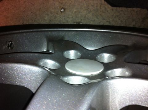 1995 Ford Mustang - This image shows a close-up view of a vehicle's wheel hub, focusing on the lug nut mounting points and the center cap area.