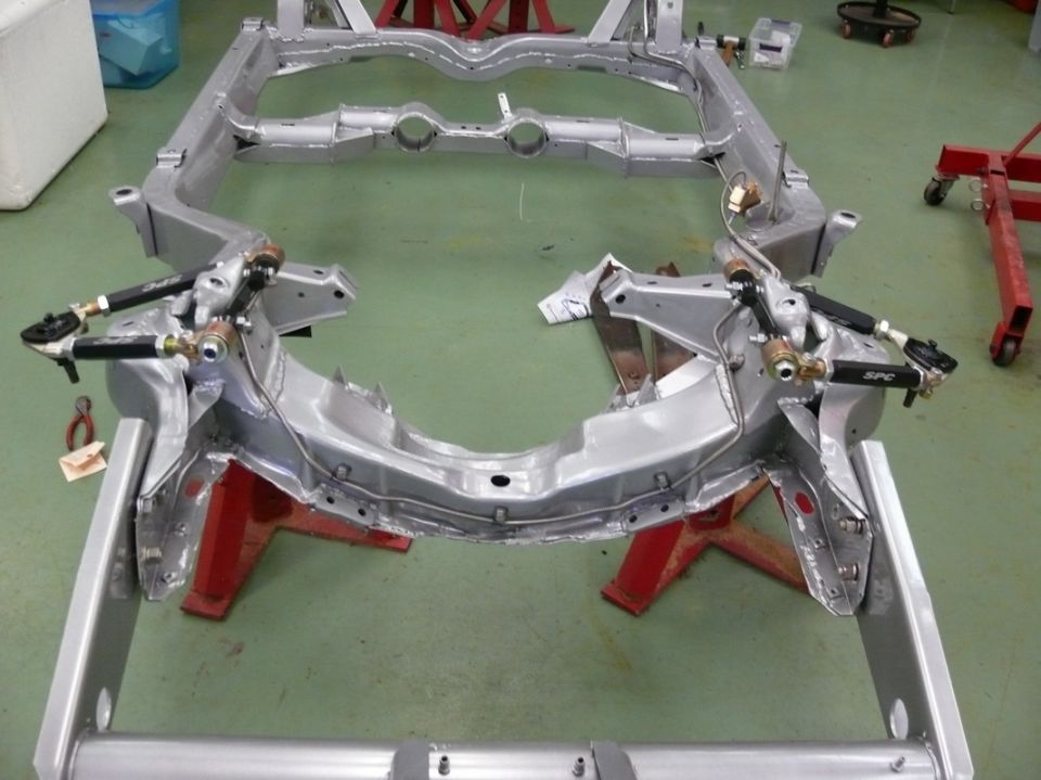 Car frame on red jack stands, showing suspension components and "SPC" branding