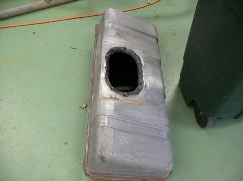1976 Chevrolet Corvette - Metal fuel tank with a black gasket around an oval opening, resting on a green floor.