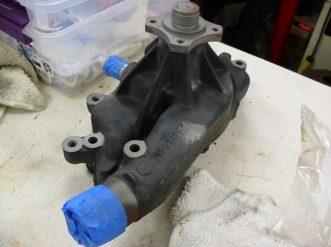 1976 Chevrolet Corvette - A car water pump is shown on a workbench, with blue tape covering some of its outlets.