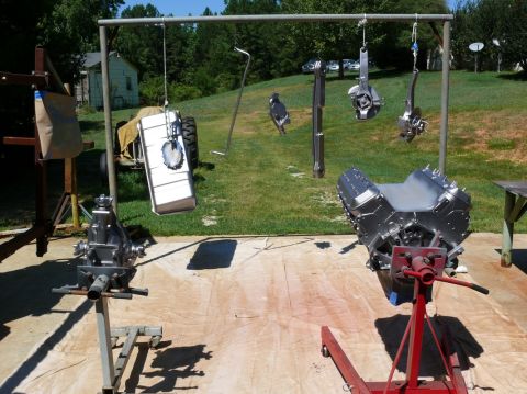 1976 Chevrolet Corvette - Car engine and transmission are displayed outdoors with other parts hanging nearby.