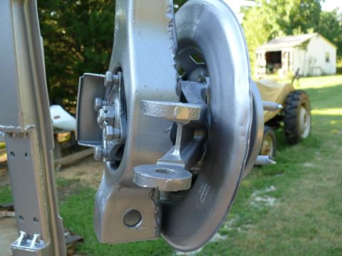 1976 Chevrolet Corvette - A close-up view of a painted vehicle suspension part is shown, with a tractor and a building in the background.