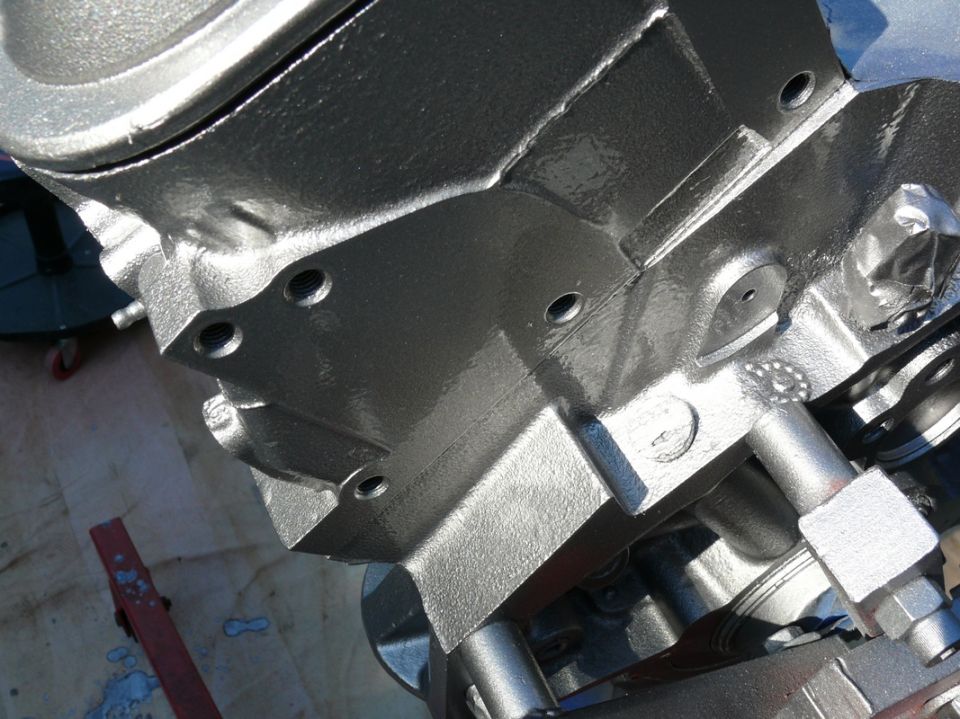 Close-up of a silver-painted engine block with bolt holes visible