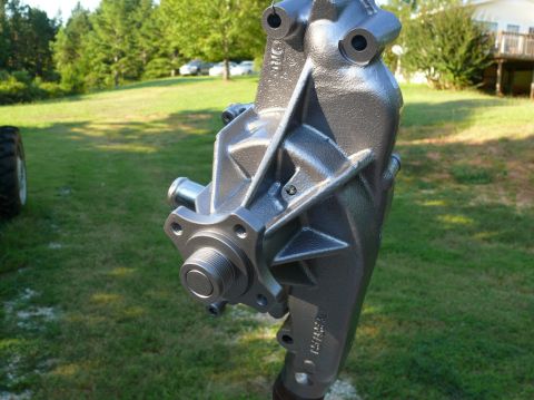 1976 Chevrolet Corvette - A metallic water pump is shown in an outdoor setting with grass and trees in the background.