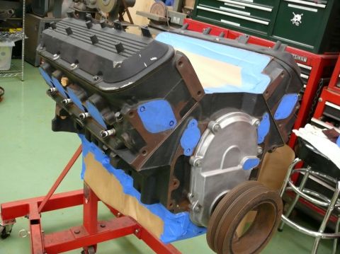 1976 Chevrolet Corvette - Engine block on a red stand, partially covered with blue painter's tape and brown paper.