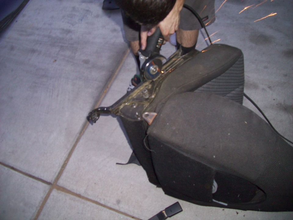 Car seat frame being cut with an angle grinder, sparks flying