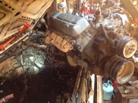 1989 Ford Bronco - Engine removal in progress, with the hood open and the engine suspended by a hoist.