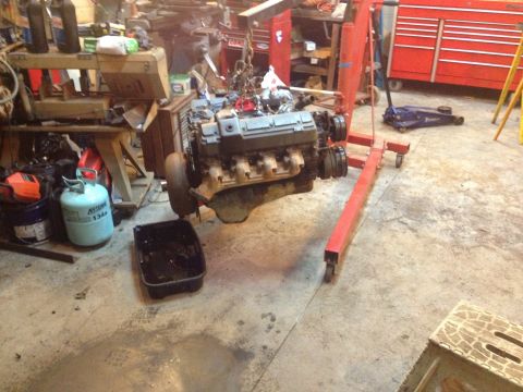 1989 Ford Bronco - Engine hoist holding a V8 engine over a drain pan in a workshop environment.
