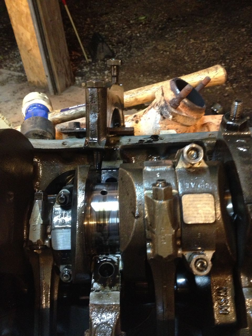 Engine block bottom end during rebuild showing crankshaft, rod caps and shop tools