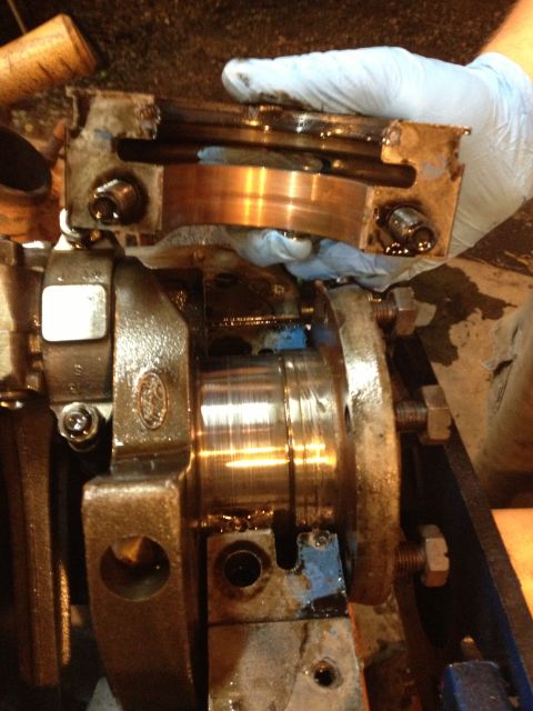 1989 Ford Bronco - Mechanic's hands in gloves work on an engine's crankshaft and bearing assembly, showing internal engine components.