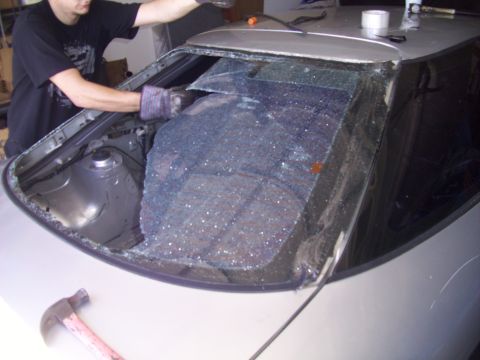 1995 Ford Probe - Removing the shattered rear window of a 1995 Ford Probe, with tools visible on the car's body.