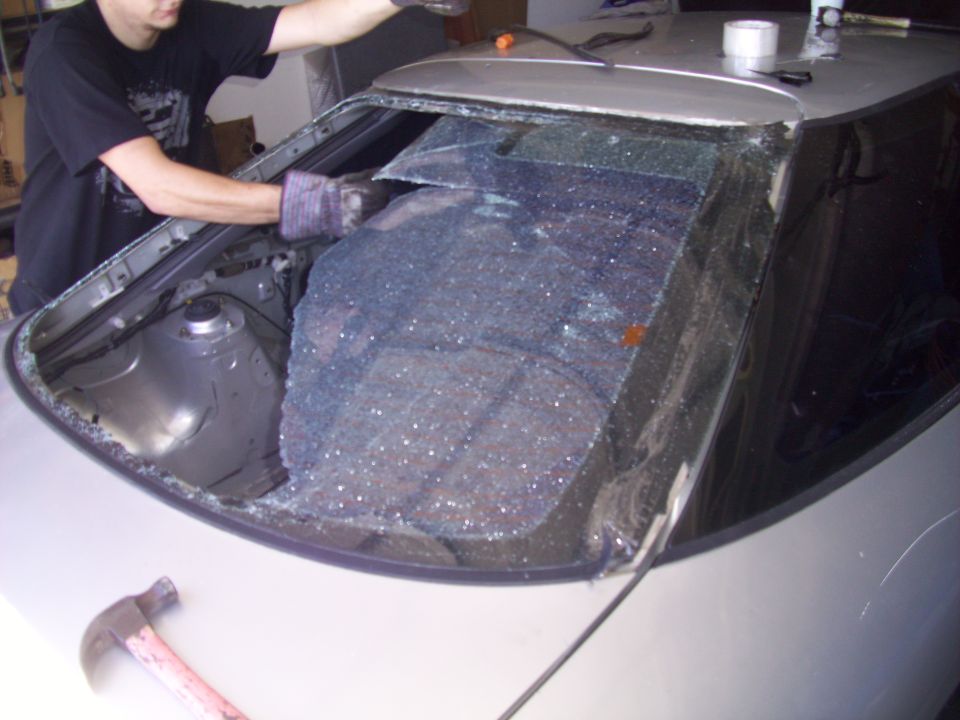 1995 Ford Probe rear window removal in progress, person wearing gloves is cleaning the frame
