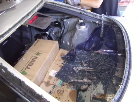 1995 Ford Probe - The rear window of a car has been broken, with glass fragments scattered inside the trunk amongst some boxes.