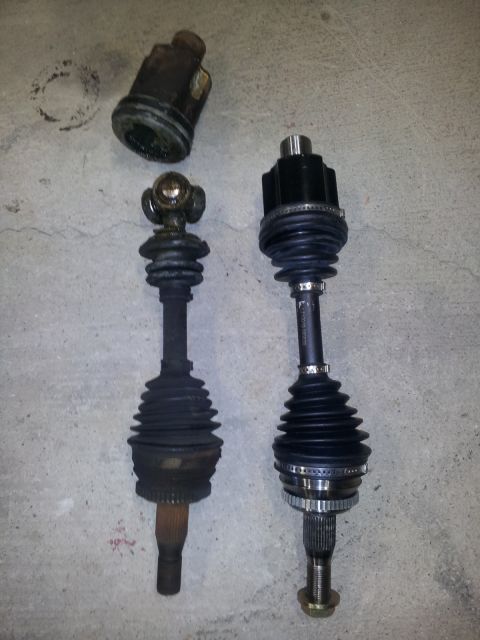 2002 Chrysler 300M - Comparison of a new CV axle with an older, worn one, laid out on a concrete surface.