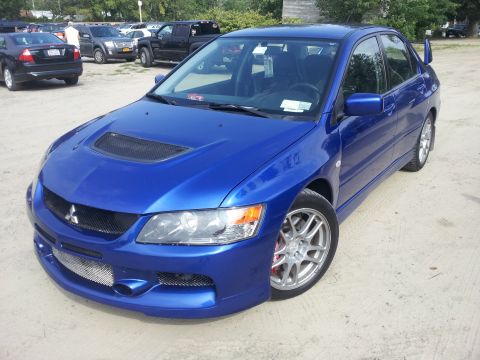 2006 Mitsubishi Evolution - A blue Mitsubishi Lancer Evolution VIII is parked in a lot with other vehicles in the background.