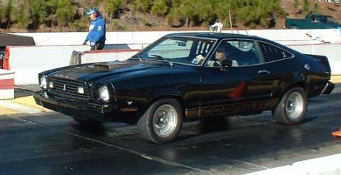 1977 Ford Mustang II - Black 1977 Ford Mustang II Cobra II on a drag strip with a person in the driver's seat.