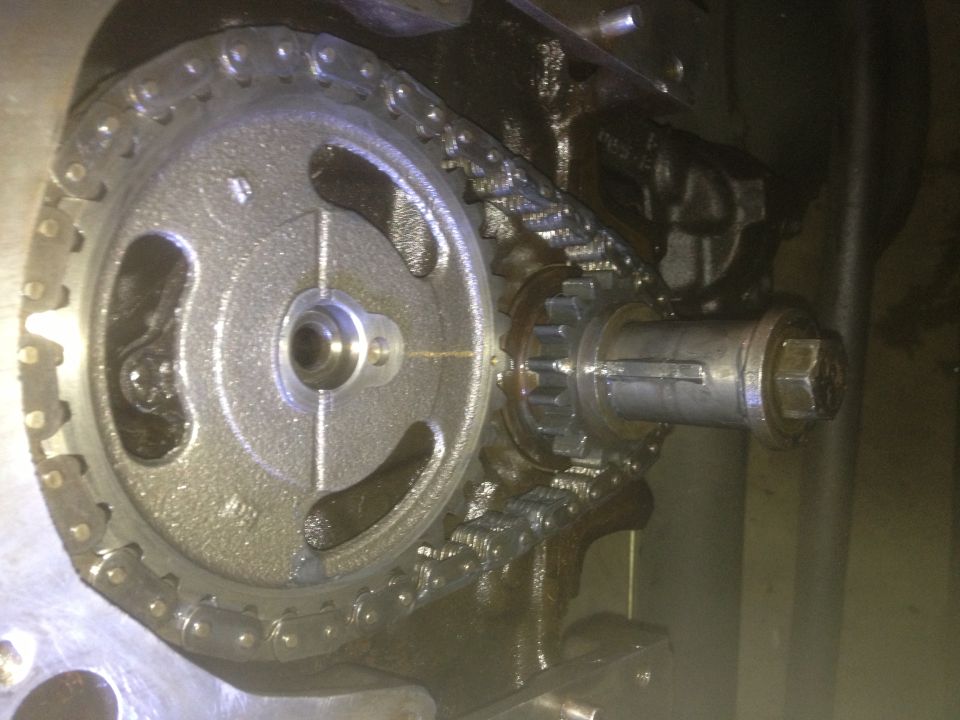 Engine timing chain and gears with a large sprocket on the left and a smaller gear on a shaft to the right