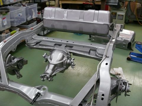 1976 Chevrolet Corvette - The chassis of a vehicle, including the differential and fuel tank, is shown in a workshop setting.
