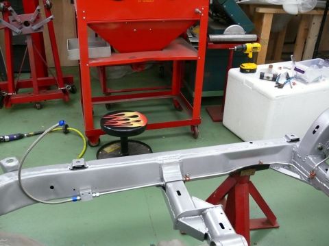 1976 Chevrolet Corvette - Car frame assembly supported by jack stands, with workshop equipment visible.