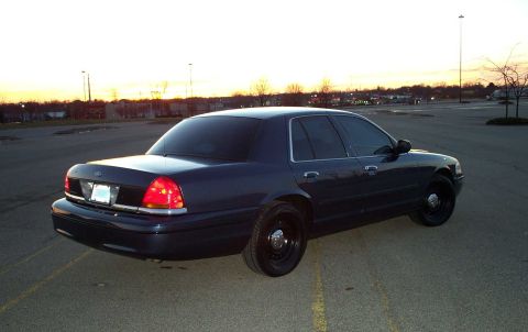 1998 Ford Crown Victoria - A dark blue 1998 Ford Crown Victoria sedan is parked in an empty lot as the sun sets.