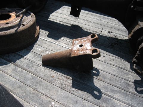 Rusty metal part with two holes on a wooden surface